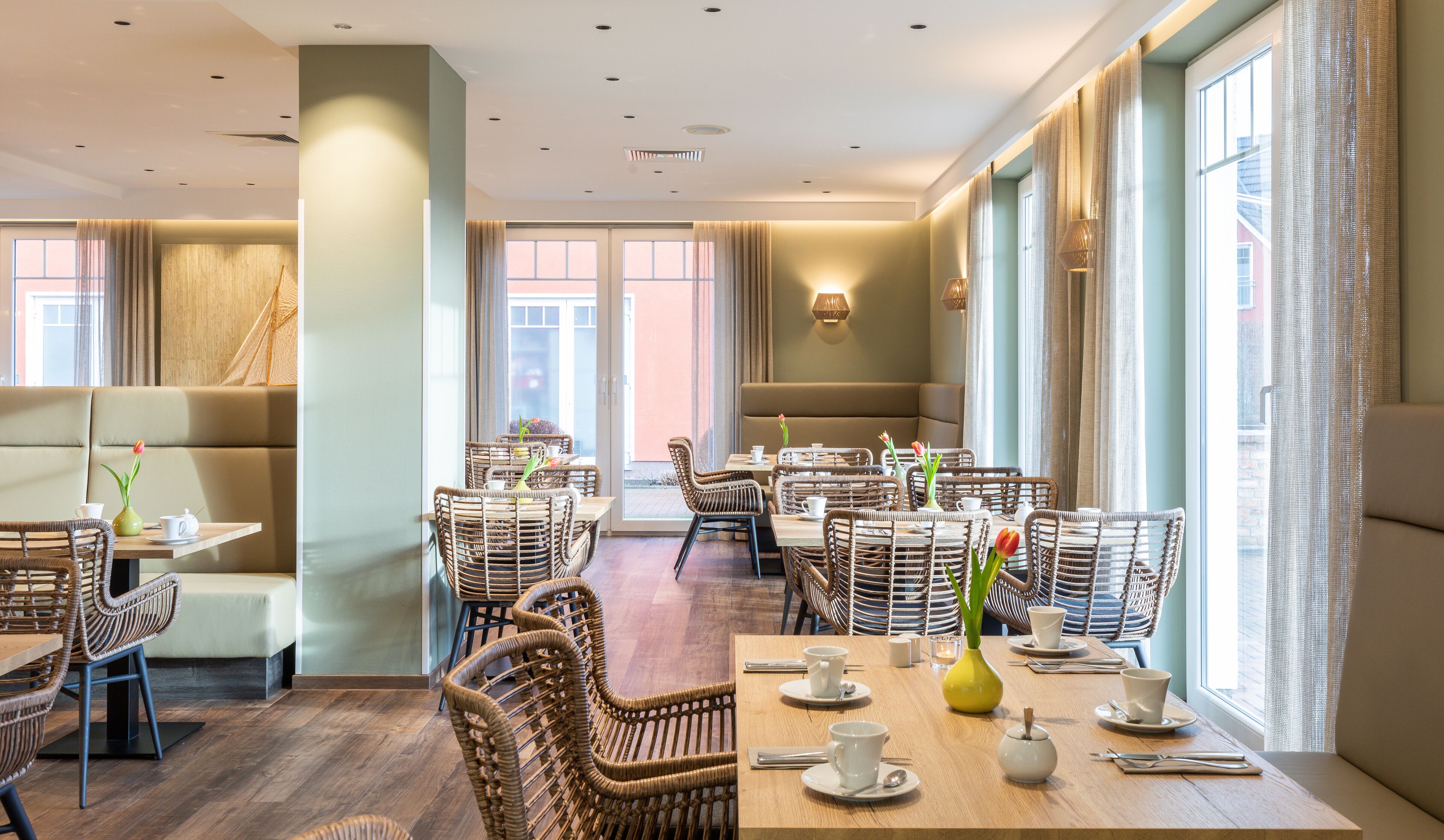 Un restaurant moderne avec des meubles en osier, de grandes fenêtres et un coin salon accueillant.