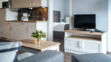Une chambre d’hôtel moderne dotée d’une kitchenette, d’un téléviseur à écran plat et d’un petit coin repas.