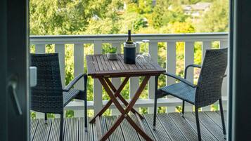 Eine Holzterrasse mit Tisch und zwei Stühlen, einer Flasche und einem Weinglas.