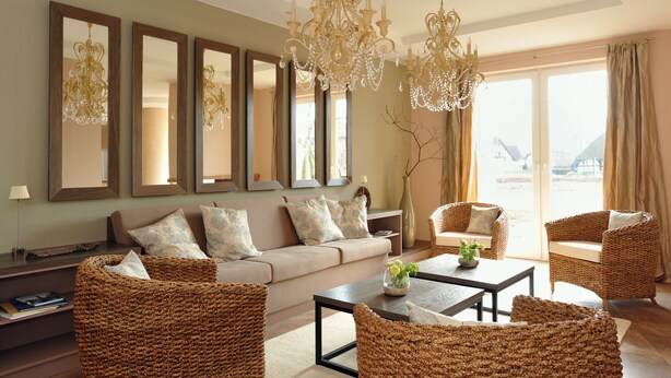A spacious living room with a beige sofa, wicker chairs, a coffee table, and a chandelier.