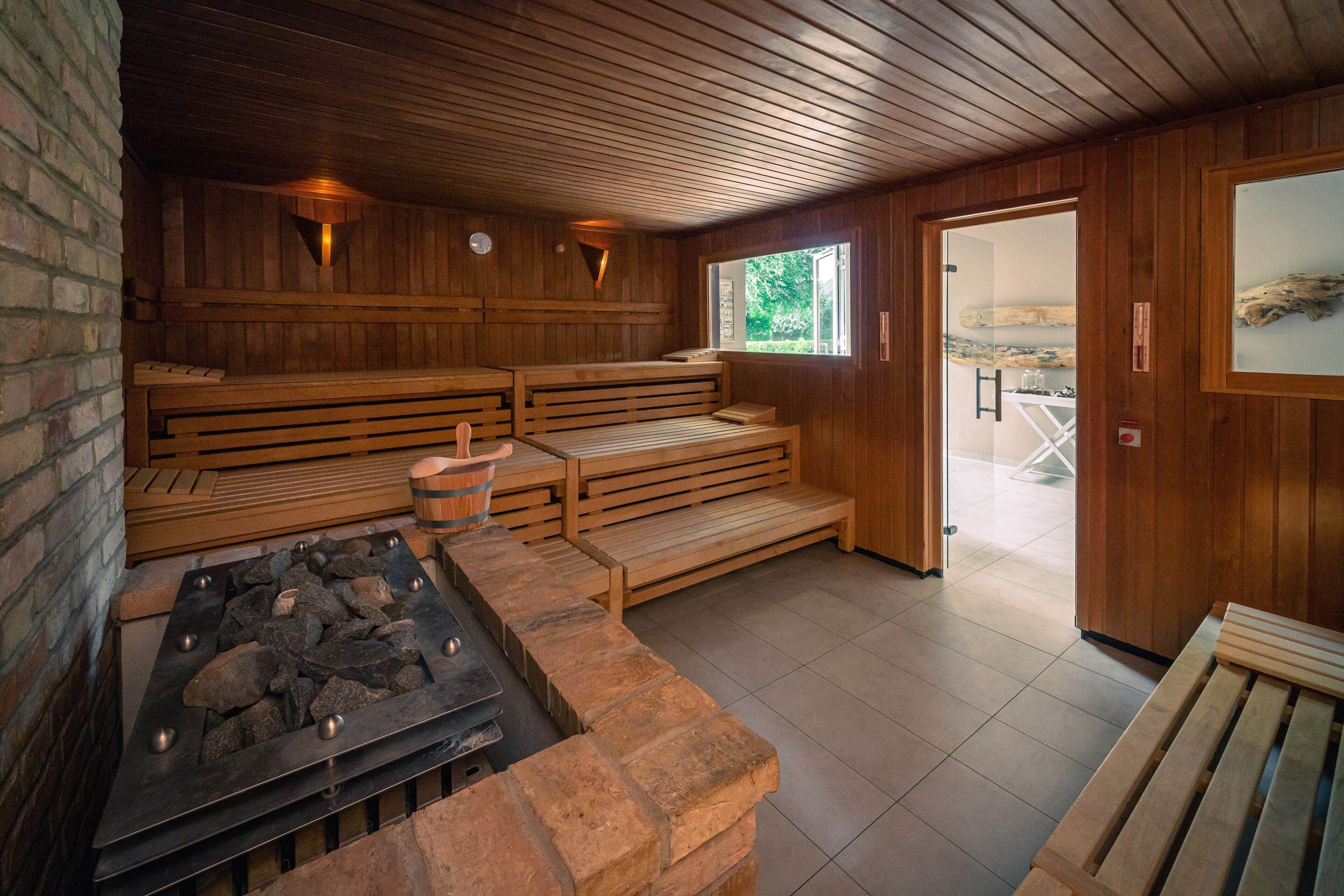Una sauna con bancos de madera, una bañera de hidromasaje de piedra y techo de madera.
