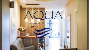 A reception area with a chair, a Christmas tree, and a sign that reads "AQUA Spa & Kosmetik".