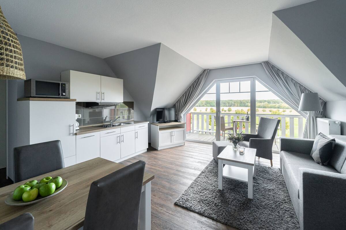 A modern apartment with a kitchen, dining area, and a balcony with a view.