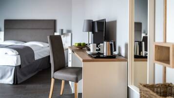 Una habitación de hotel moderna con una cama, un escritorio con una computadora portátil, una cafetera y un televisor.
