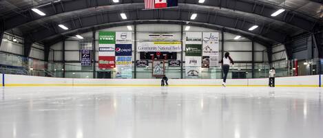 An indoor ice rink with banners advertising various brands and a scoreboard.