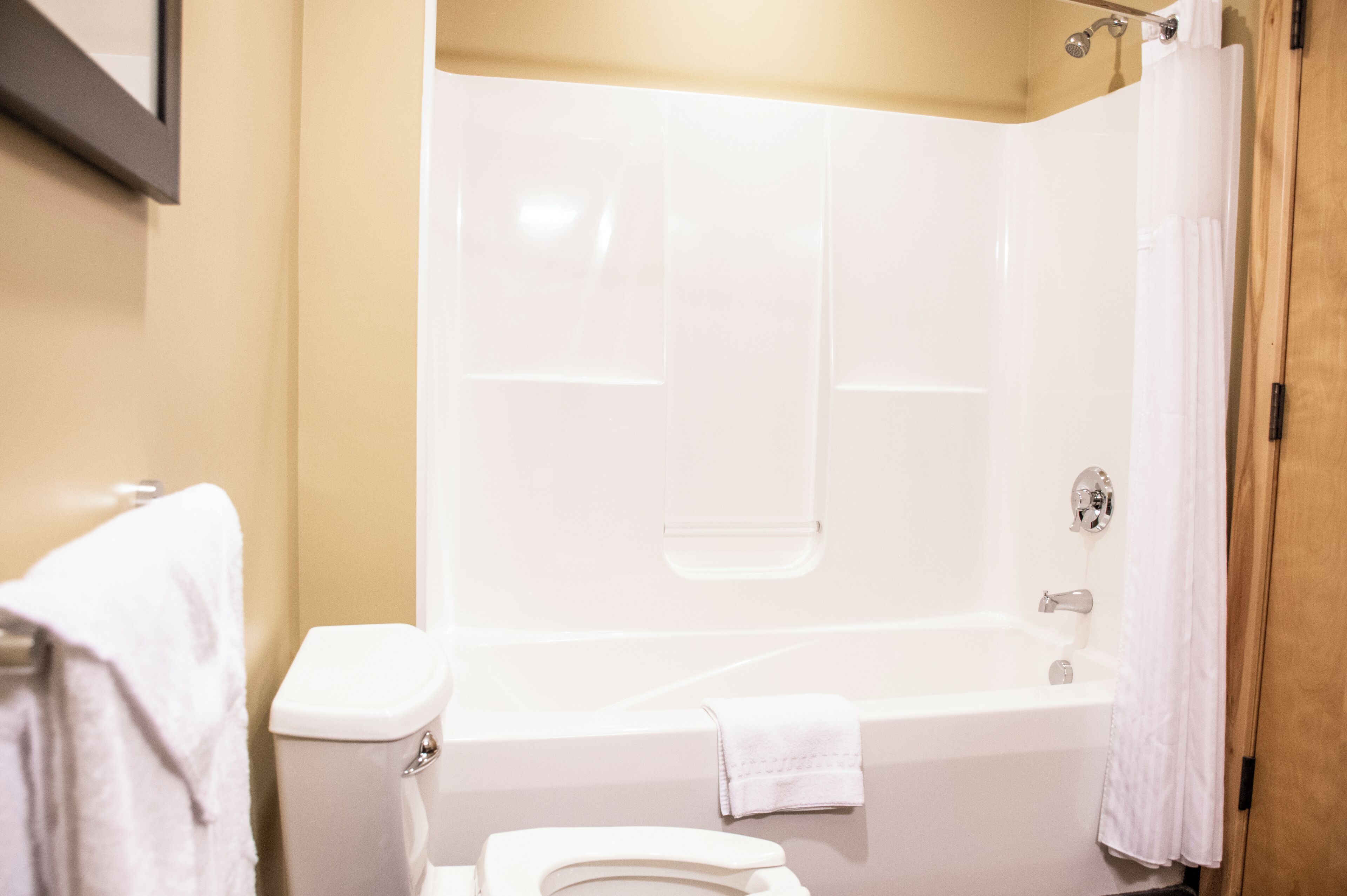 A bathroom with a white bathtub, a toilet, and a shower curtain.