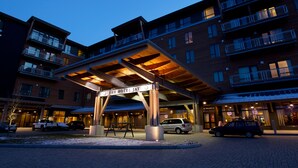 A multi-story hotel with a covered entrance, outdoor parking, and balconies. - Jay Peak Resort (North Troy)
