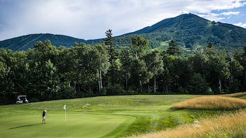 Golfers can enjoy a round on the lush green course surrounded by tall trees.