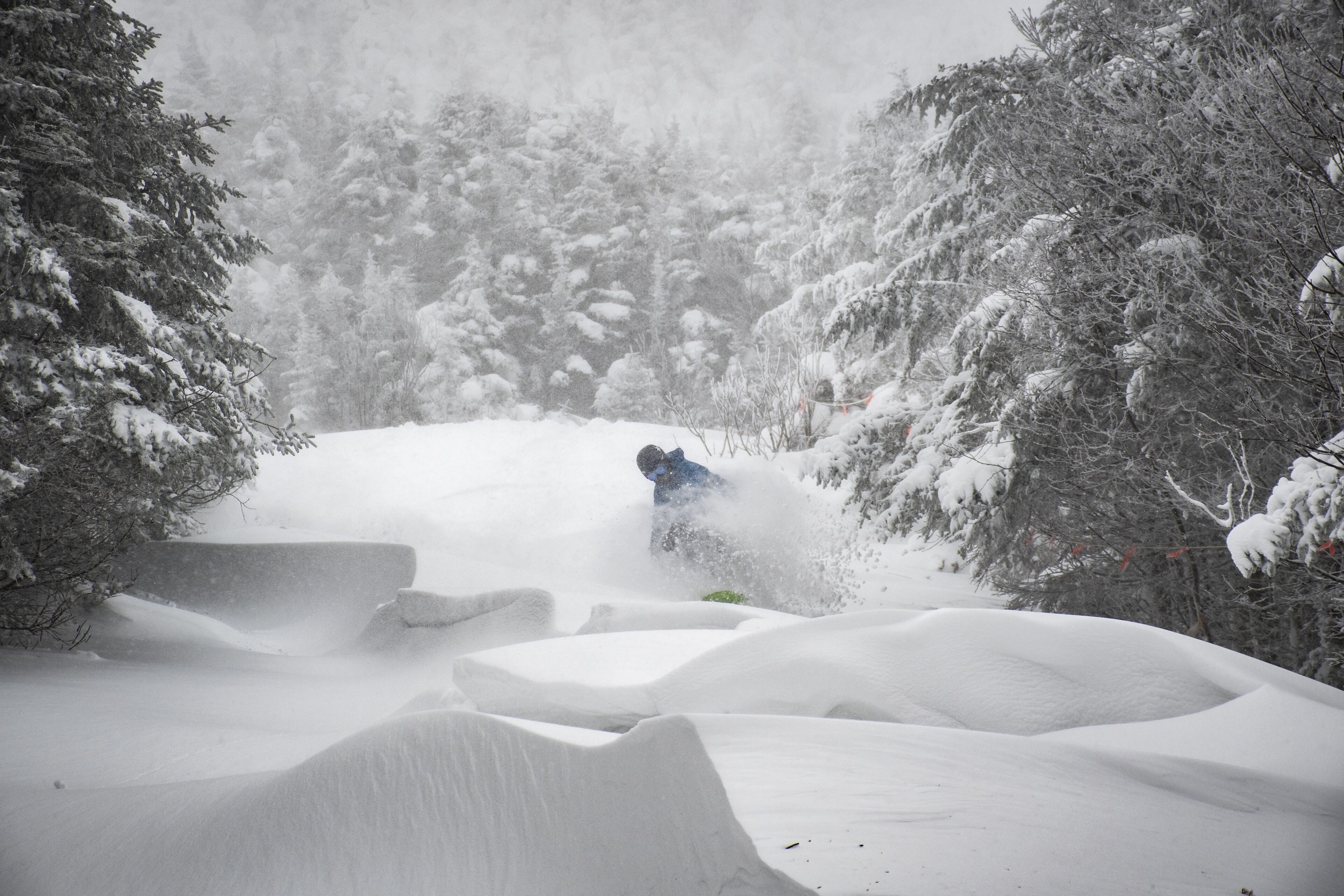 A snowy landscape with a person skiing down a snow-covered slope.