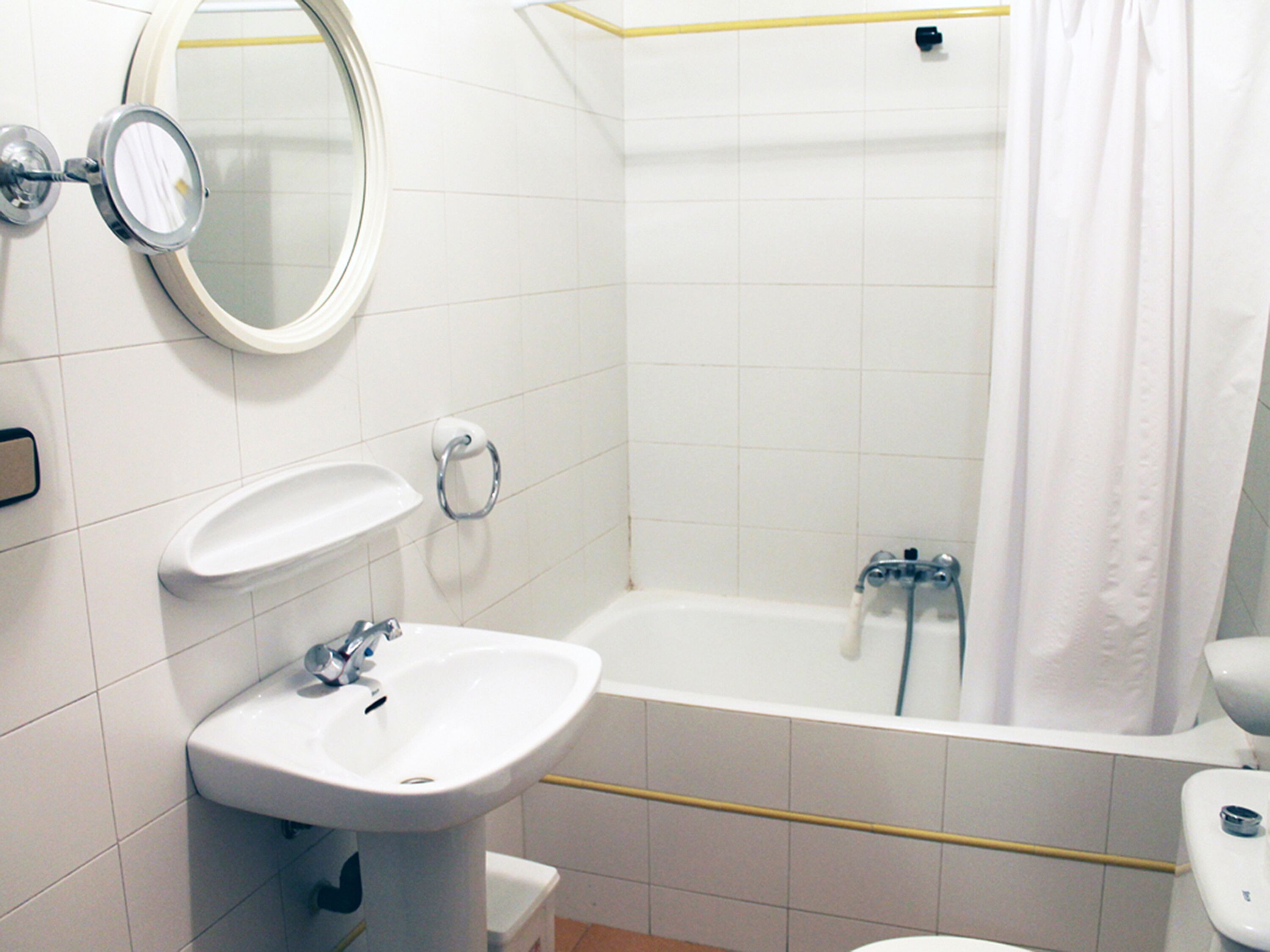 Un baño con lavamanos, espejo y bañera.
