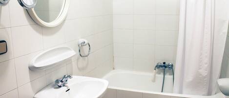 Un baño con lavamanos, espejo y bañera.