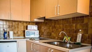 Una cocina con armarios de madera, microondas, pileta y escurreplatos.