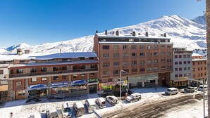 Un edificio de varios pisos con una montaña nevada al fondo.