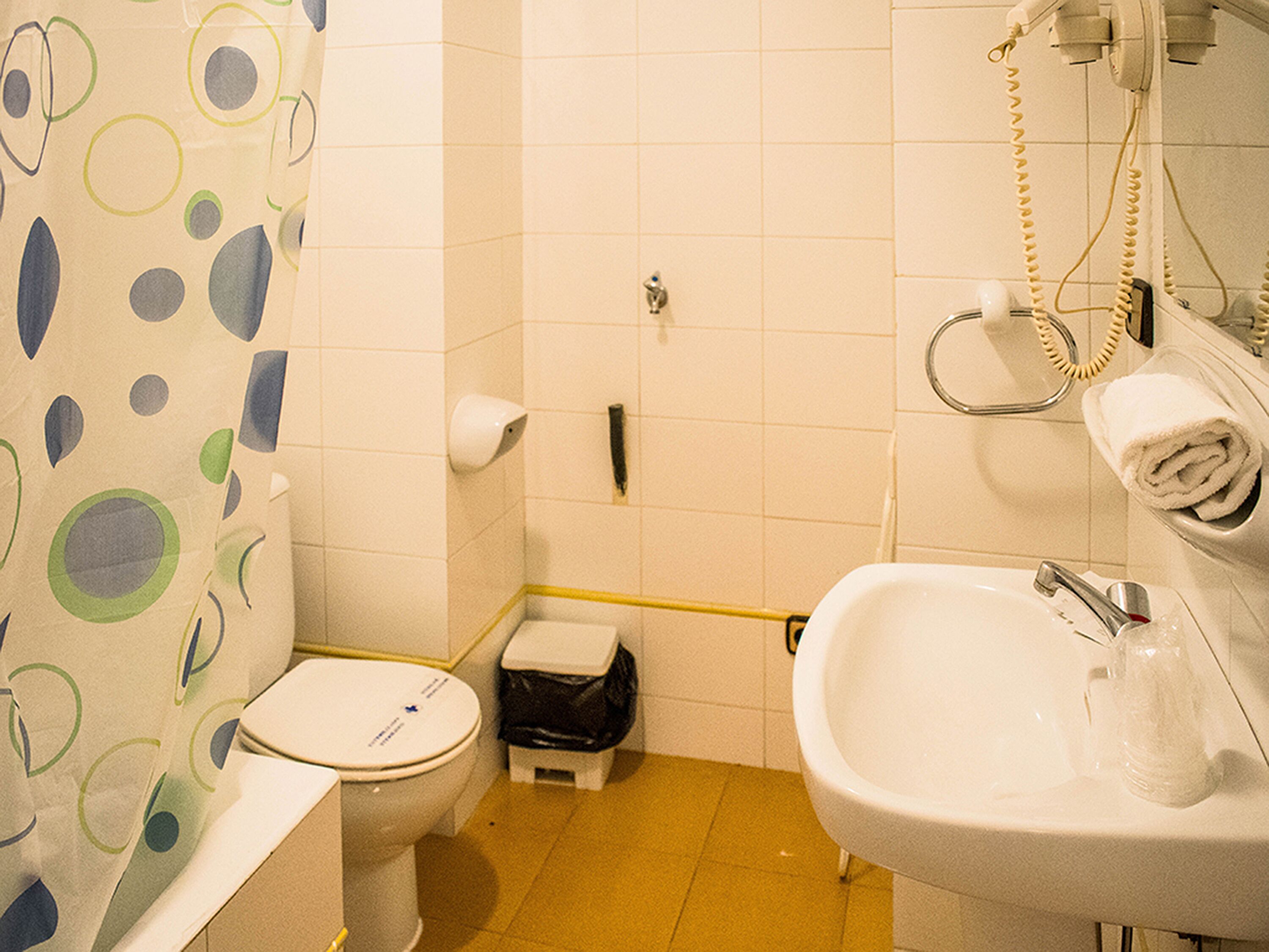 Une salle de bain équipée de toilettes, d’un lavabo et d’un porte-serviettes.