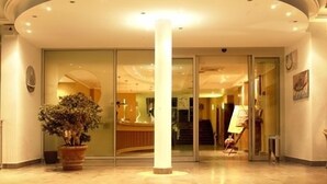 A hotel lobby with a reception desk, a large column, and a staircase leading to the upper floors. - Casa del Mar (Roseto degli Abruzzi)