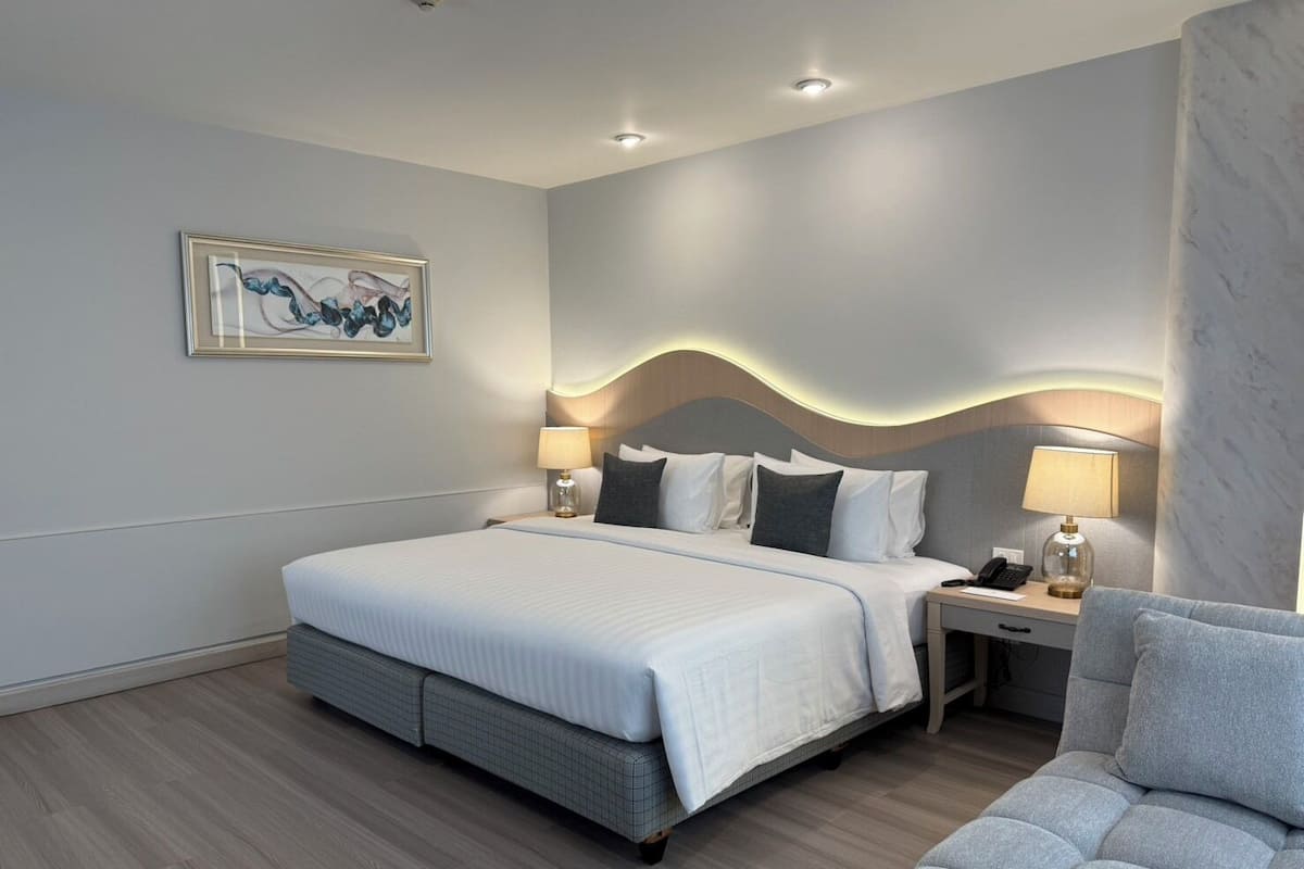 Moderni hotellihuone, jossa on suuri sänky, kaksi yöpöytää, työpöytä ja tuoli.