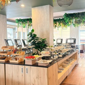 A buffet setup with various food items and condiments, a large potted plant, and seating arrangements. - Empress Pattaya Hotel (Pattaya)