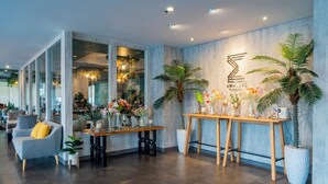 Um hall de hotel moderno com balcão de recepção, área de estar e plantas decorativas.
