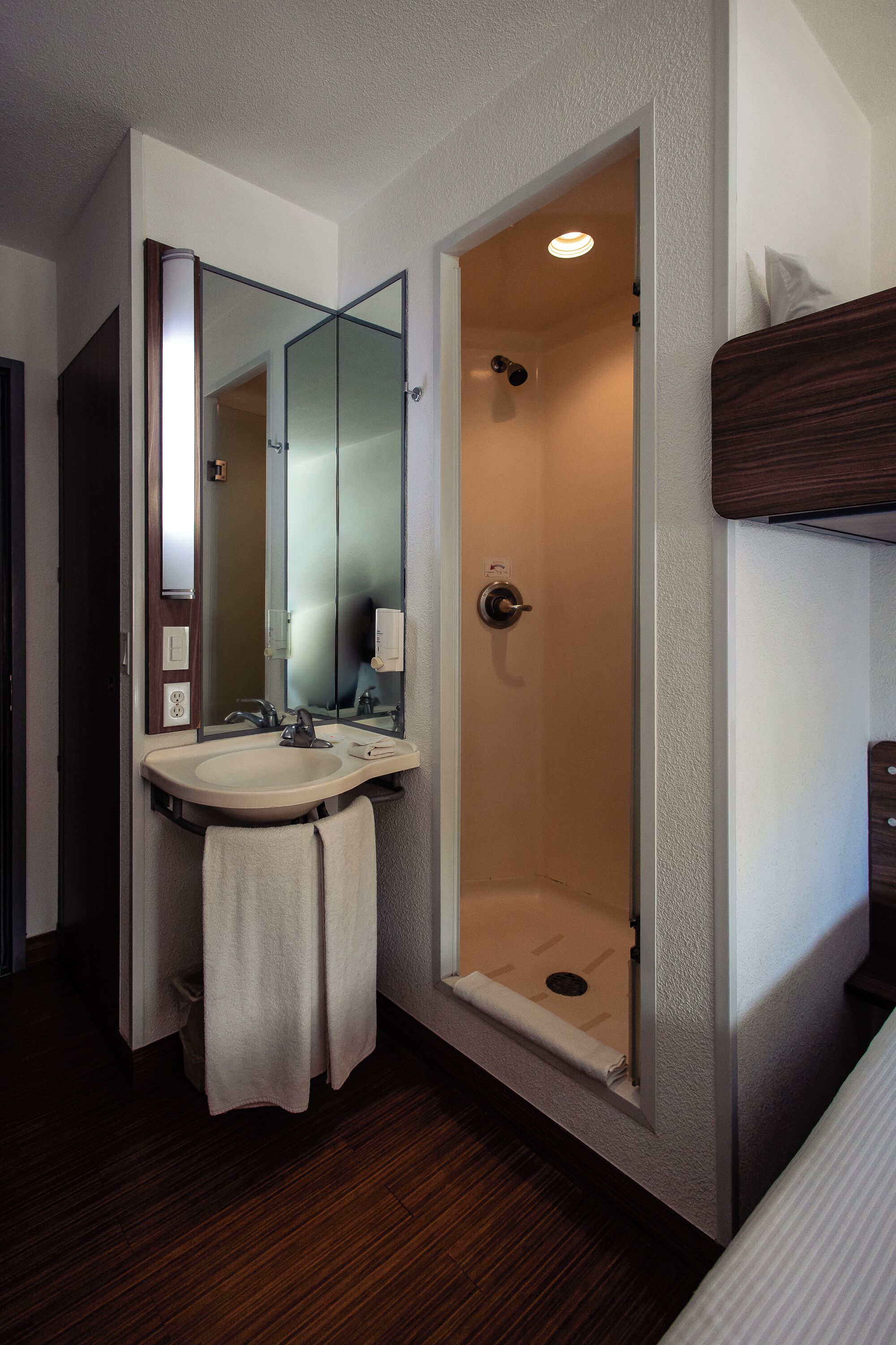 A bathroom with a sink, mirror, and shower.