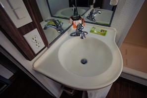 Un lavabo de salle de bain avec un miroir, un robinet et un distributeur de savon.