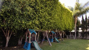 A playground with swings and slides, surrounded by trees. - Hotel Hi! Zapopan (Zapopan)
