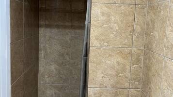 Ducha con pared de azulejos y cabezal metálico.