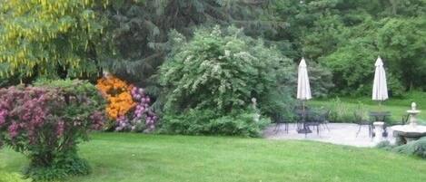 A well-maintained garden with a variety of plants and a seating area with umbrellas.