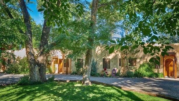 A rustic building with multiple doors and windows, surrounded by lush greenery and trees.
