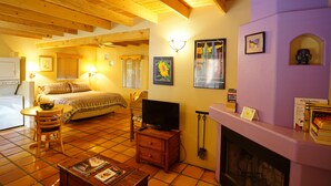 A cozy room with a bed, a television, a fireplace, and a dining area.