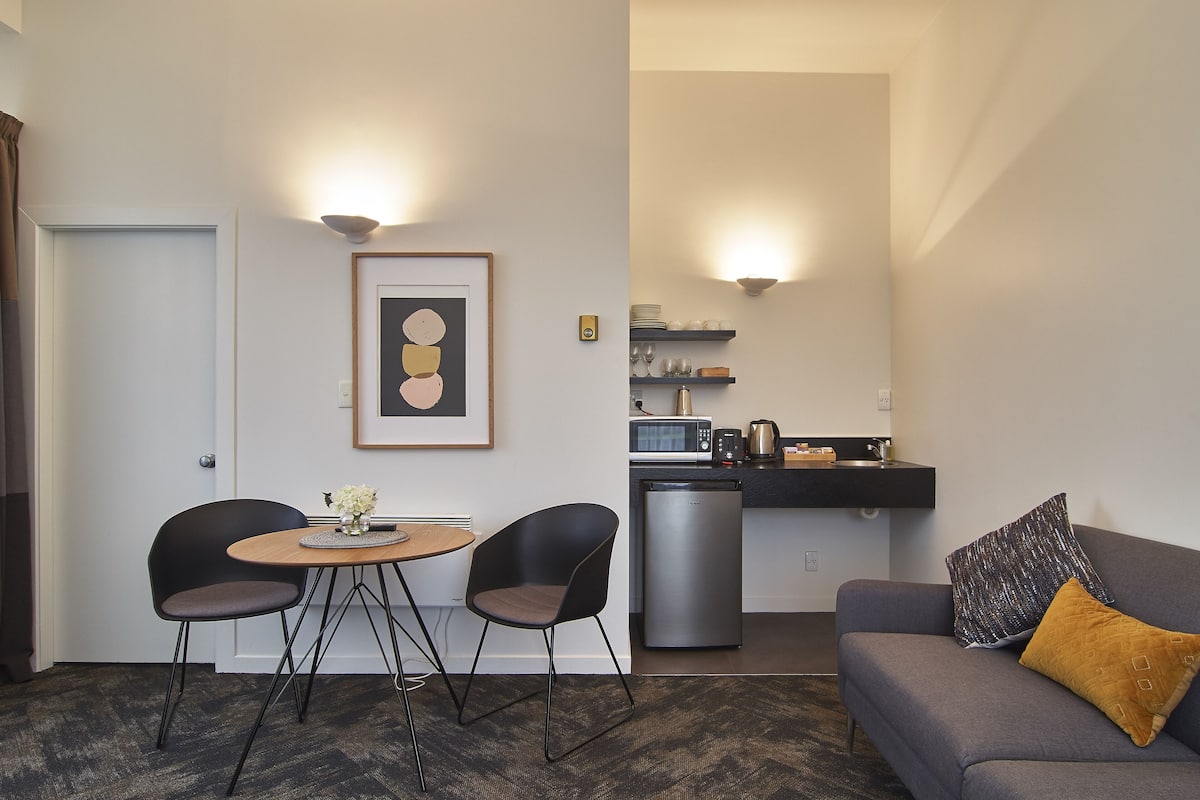 A compact living space with a dining area, kitchenette, and seating area.