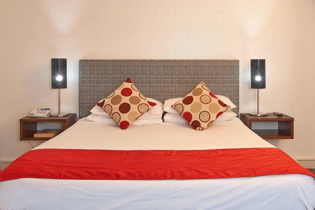 A hotel room with a large bed, two nightstands, a telephone, and two lamps.