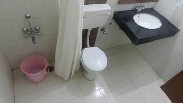 Un baño con inodoro, lavamanos y un cubo rosa.