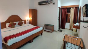 Habitación de hotel con cama, escritorio, aire acondicionado, televisor y armario.