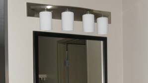 A bathroom with a black vanity, a large mirror, and three white candles on the wall.