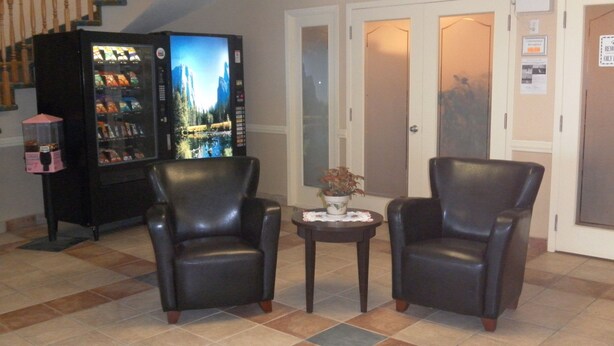 A lobby with two leather armchairs, a vending machine, and a small table with a plant.