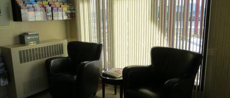 Una habitación con dos sillones de cuero negro, un radiador y una estantería con varios objetos.
