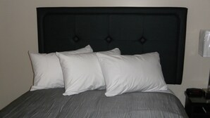 A bed with a dark headboard and four white pillows.