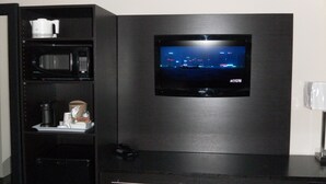 A modern kitchen with a built-in microwave, coffee maker, and a flat-screen TV mounted on the wall.