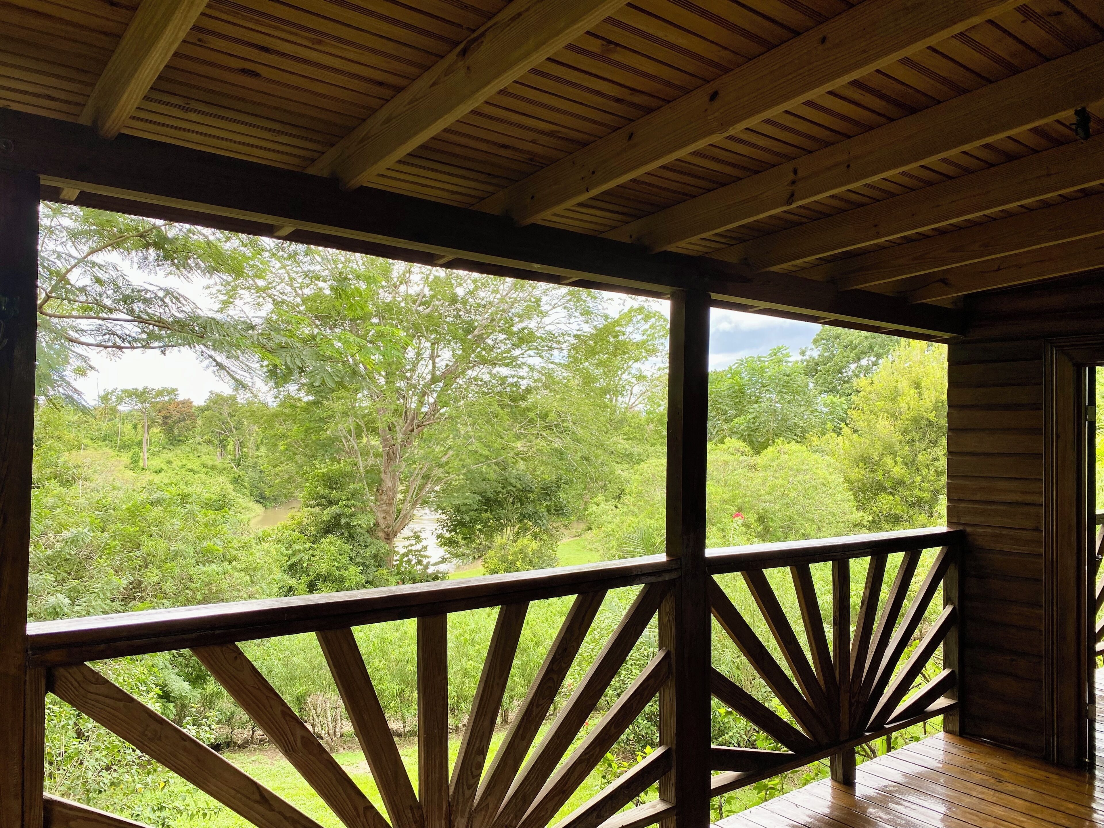 A wooden deck with a railing overlooking a lush green landscape.