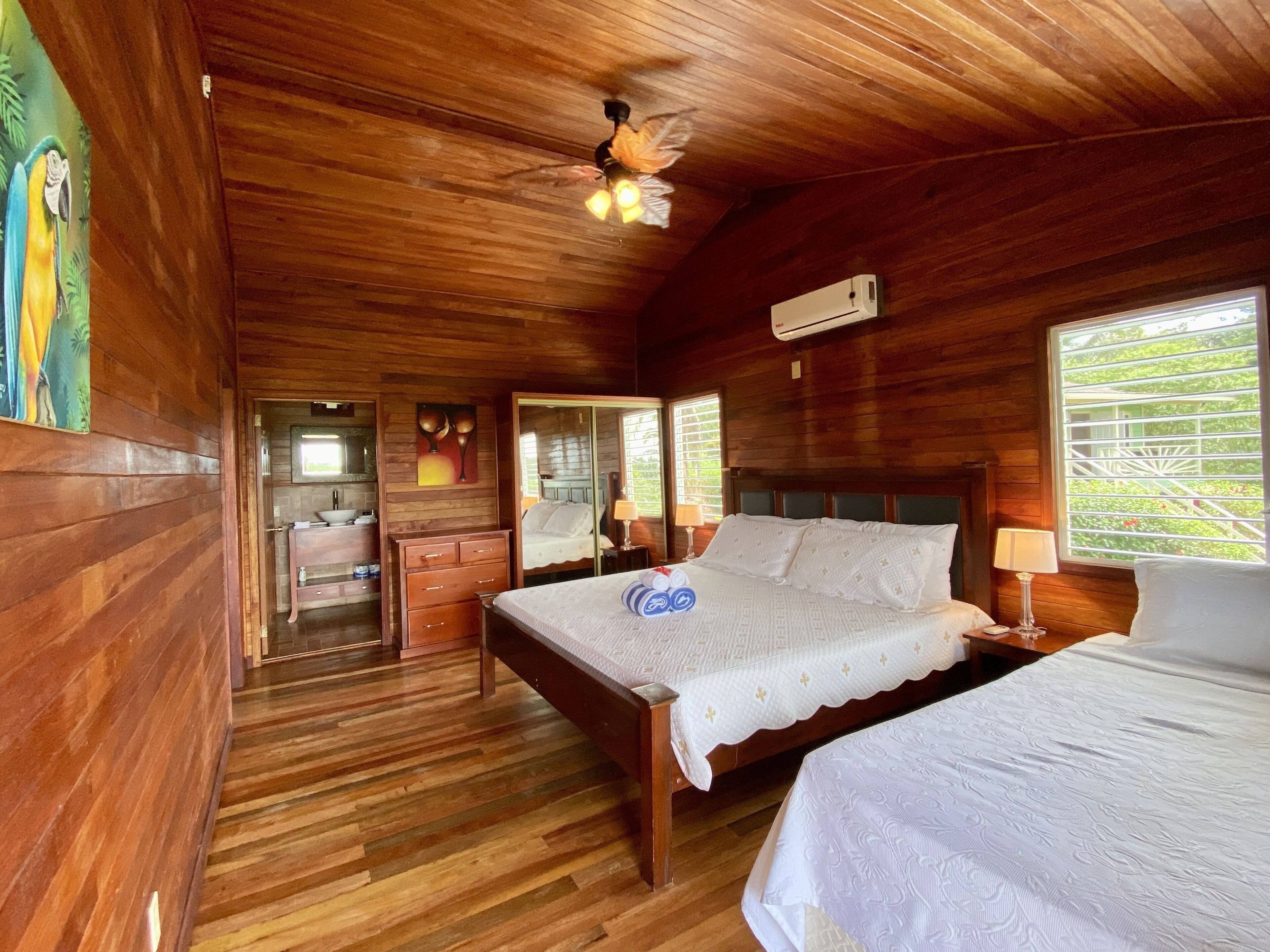 A wooden cabin room with a bed, a desk, and a bathroom.