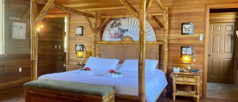 A traditional wooden four-poster bed with a canopy, a bedside table with a lamp, and a small wooden chest.