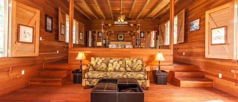 Un intérieur spacieux, avec des éléments en bois, comprenant un canapé, un pouf et des lampes.