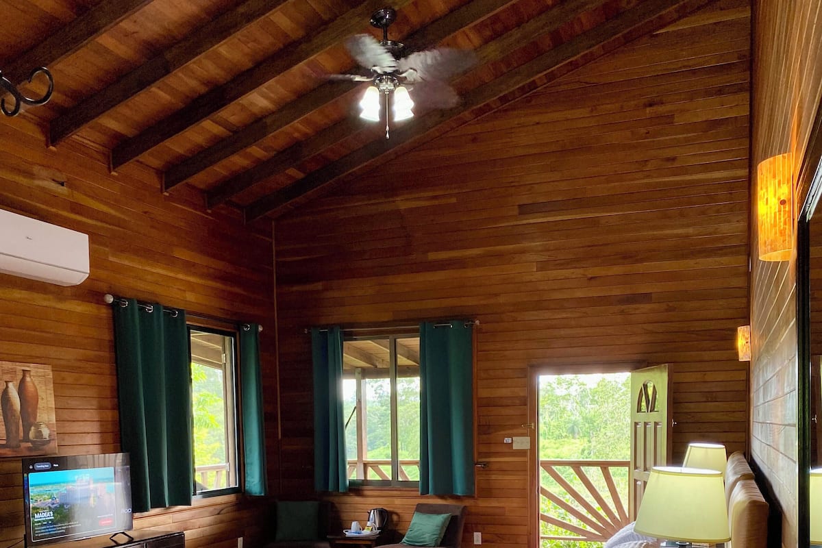 A wooden cabin bedroom with a bed, bedside table, and a ceiling fan.