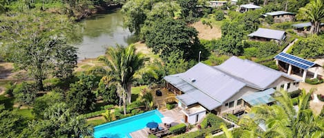 Un complexe hôtelier doté d’une piscine, de panneaux solaires et d’une végétation luxuriante.