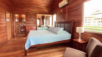 Une chambre à coucher de style cabane en bois, comprenant un lit, une table de chevet, une chaise et une fenêtre donnant sur un paysage agréable.