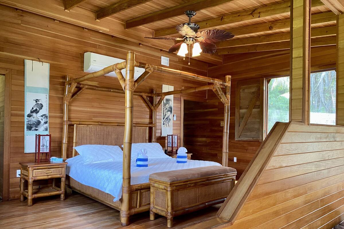A wooden four-poster bed with a canopy, a nightstand, and a bedside table.