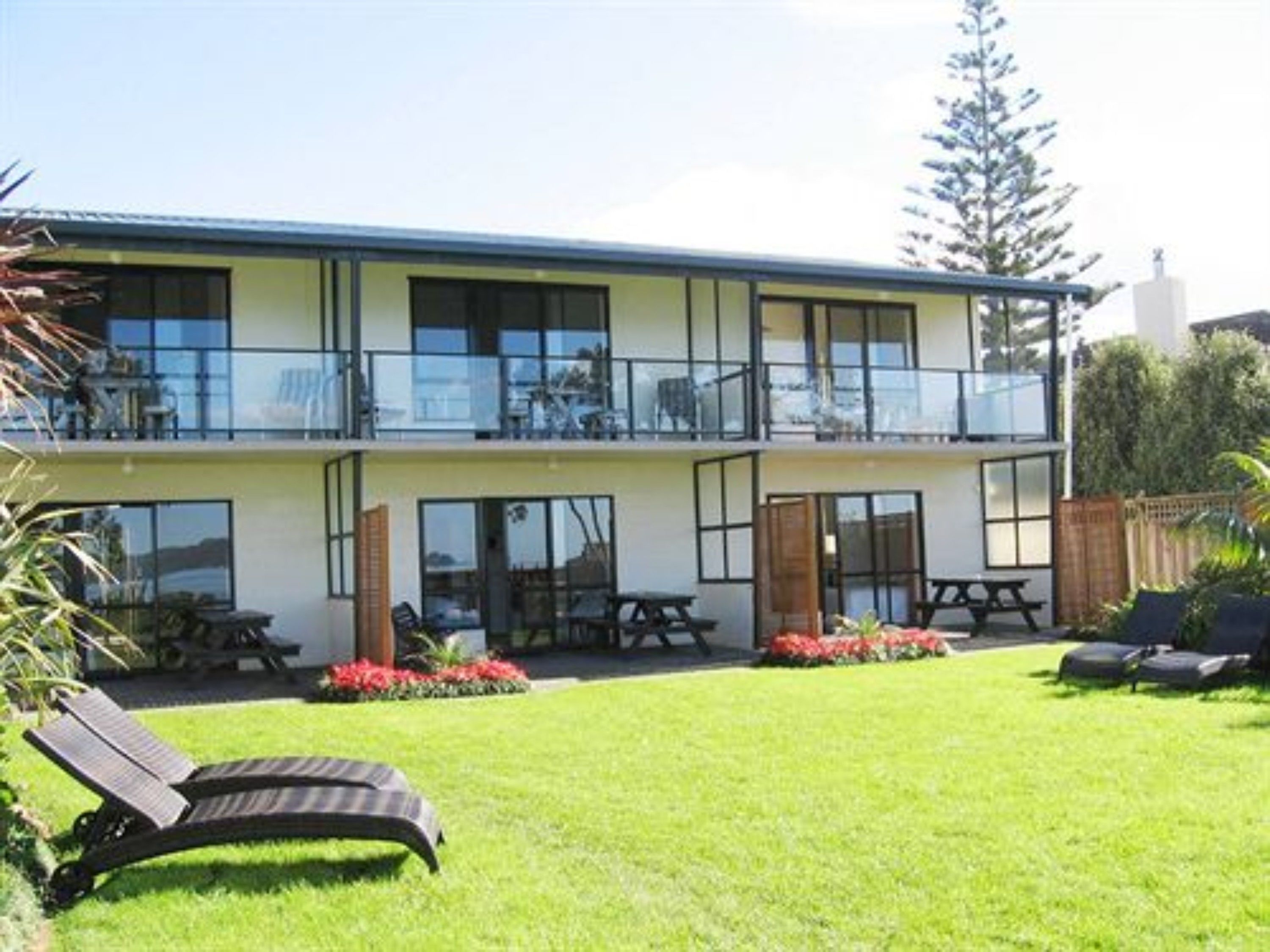 A two-story building with a balcony, outdoor seating, and a well-maintained lawn.