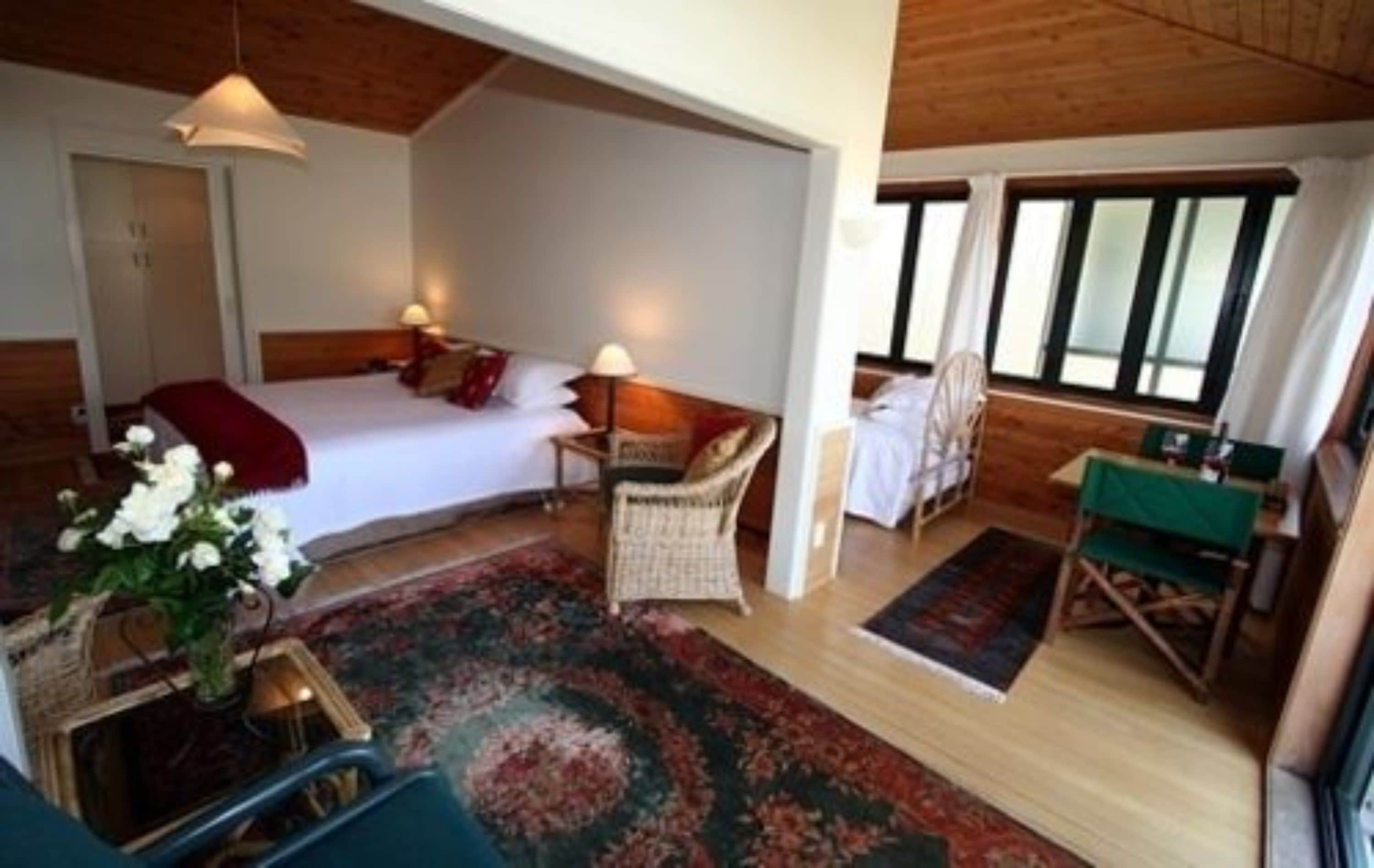 Une chambre confortable avec un lit, une table de chevet, une chaise et une petite table avec une lampe.