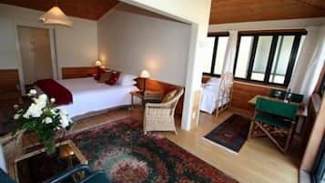 A cozy bedroom with a bed, bedside table, chair, and a small table with a lamp.