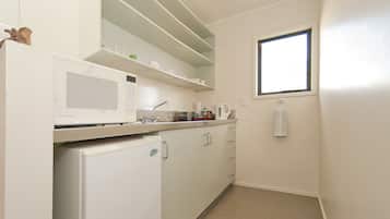 Cocina compacta con electrodomésticos blancos, una ventana y una toalla colgada en la pared.